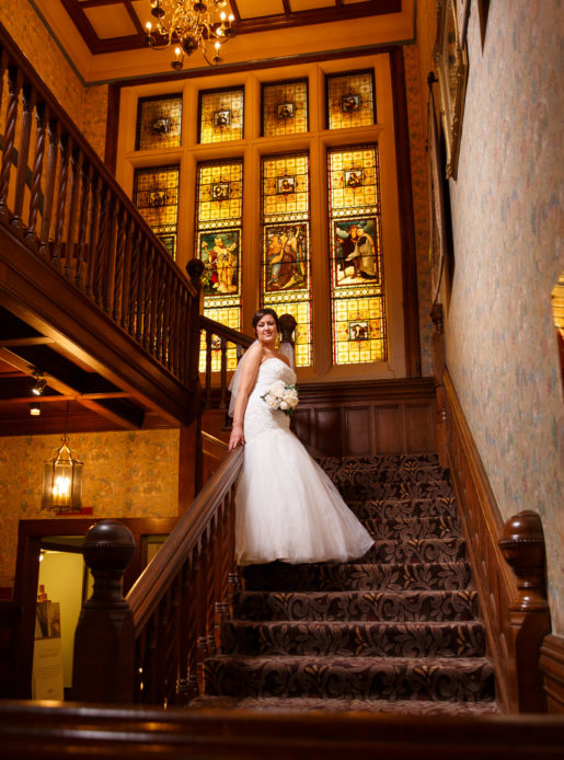 Bride standing in front of stained glass window in the stairwell at Mercure Burton Upon Trent Newton Park Hotel