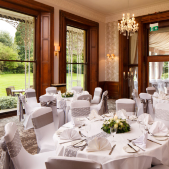 The William Morris Suite at Mercure Burton Upon Trent Newton Park Hotel, set up for a wedding breakfast, windows looking out onto grounds