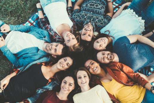 Above view of young people lying down in a circle and looking at camera
